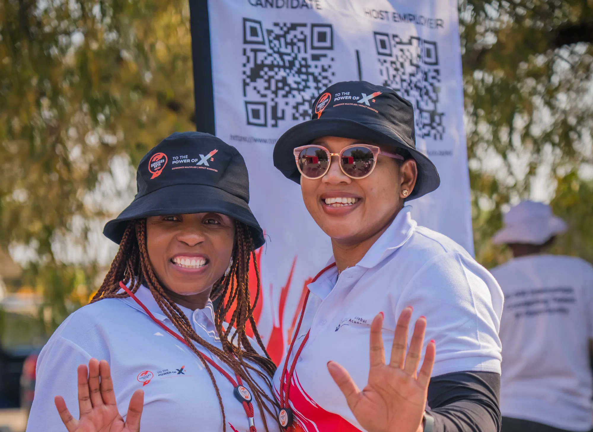 Two programme representatives at a To The Power of X² event, with Candidate and Host Employer registration signage behind them.